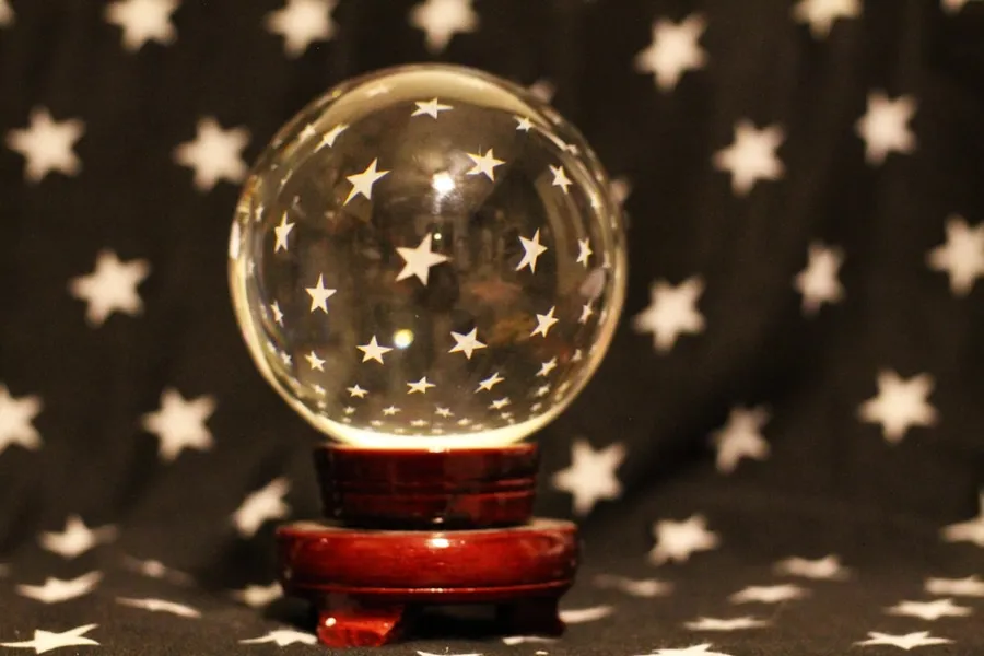 Ilustrasi mimpi ahli nujum — a snow globe sitting on top of a wooden stand