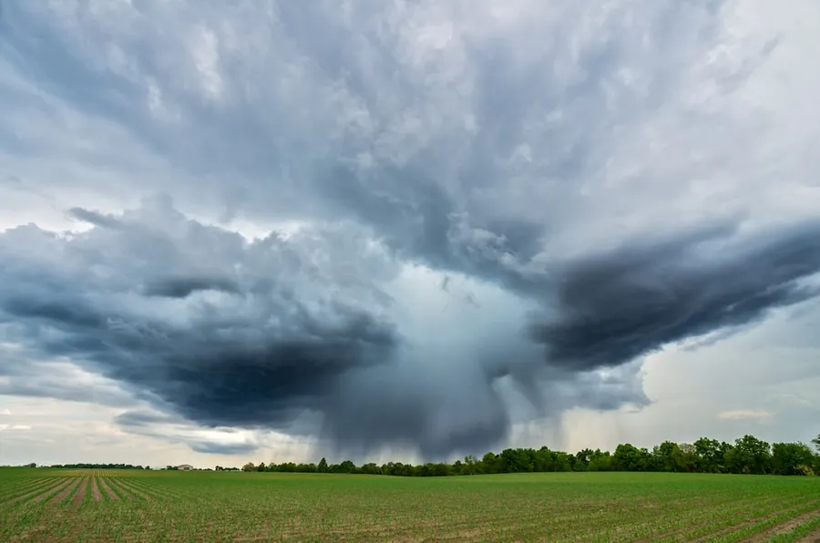 Ilustrasi mimpi angin tornado — landscape photography of a green field under a cloudy sky