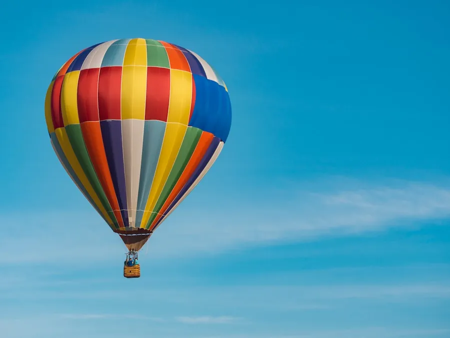 Ilustrasi mimpi balon — panning photography of flying blue, yellow, and red hot air balloon