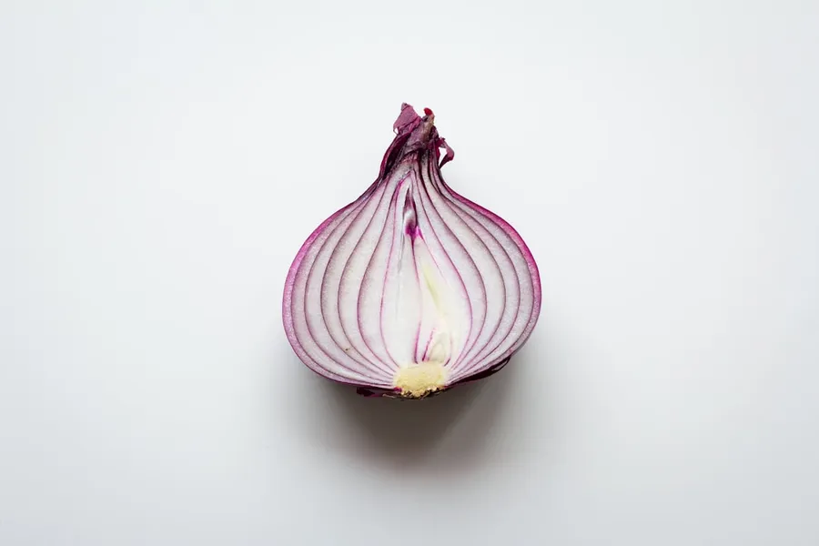 Ilustrasi mimpi bawang — pink and white garlic on white surface