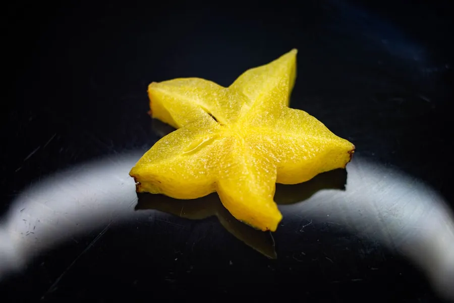 Ilustrasi mimpi belimbing — yellow star ornament on black surface