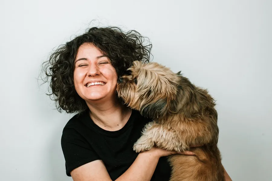 Ilustrasi mimpi anjing bercinta — dog kissing woman in black crew-neck shirt