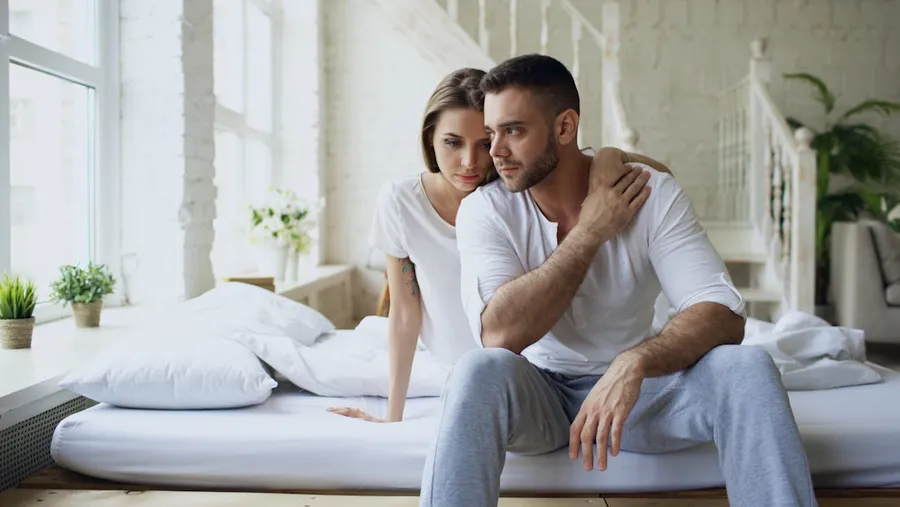 Ilustrasi mimpi cemburu — Couple sitting on a bed in a bright room