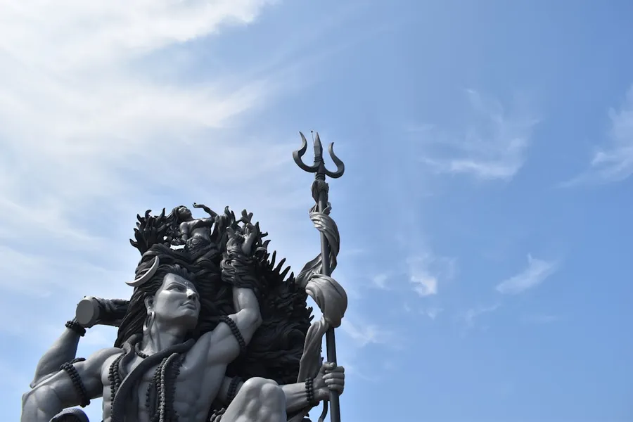 Ilustrasi mimpi dewa langit — black concrete statue under blue sky during daytime