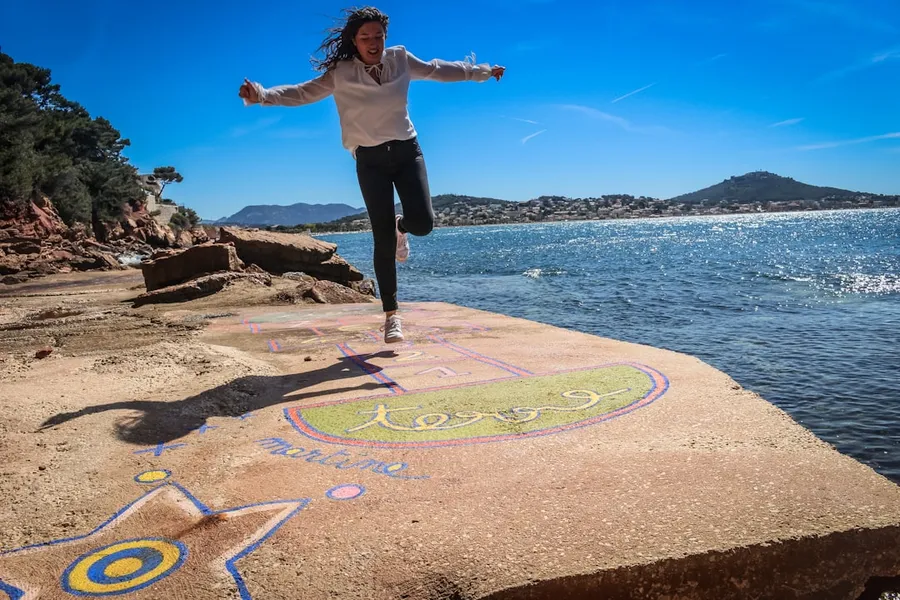 Ilustrasi mimpi engkleh — woman in white shirt and black pants standing on rock near body of water during daytime
