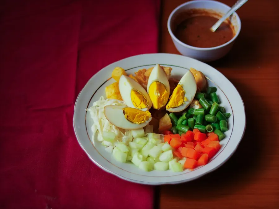Ilustrasi mimpi gado-gado — sliced veggies and egg on white ceramic plate