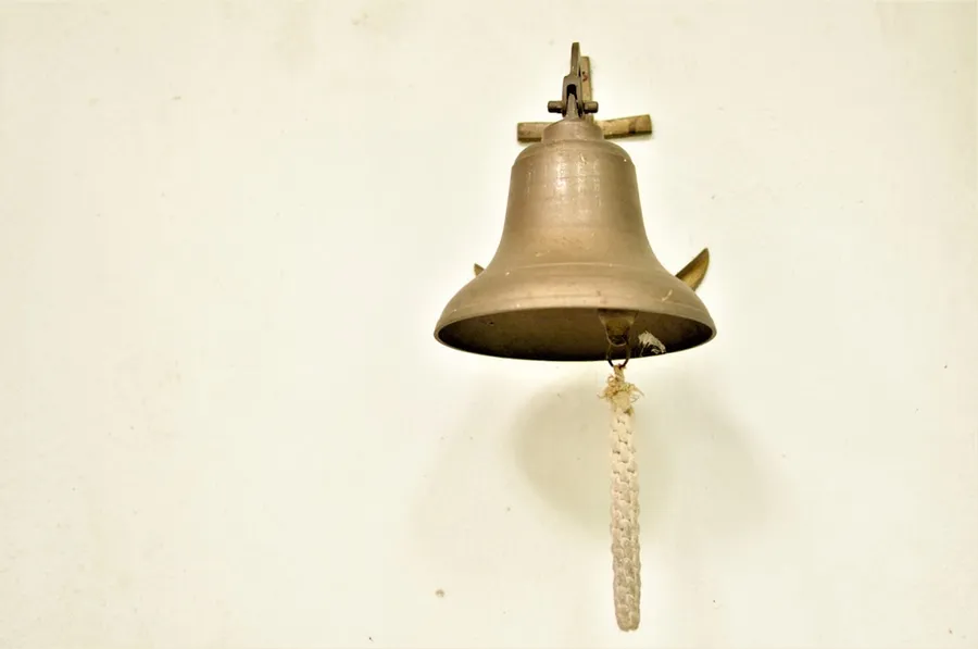 Ilustrasi mimpi lonceng — a bell hanging on a wall with a rope