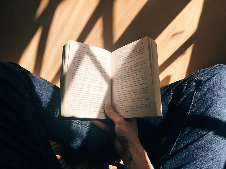 Ilustrasi mimpi membaca — person holding book sitting on brown surface