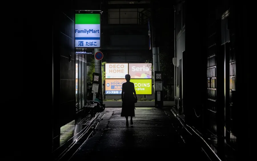 Ilustrasi mimpi pemadat — A figure walks down a dark, urban alley.