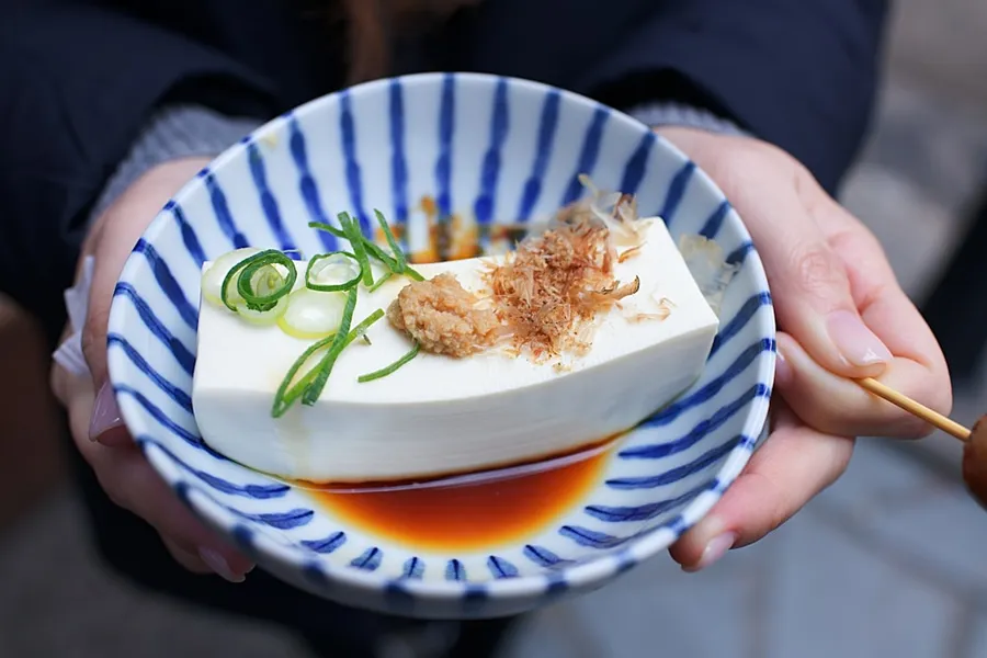 Ilustrasi mimpi tahu — person holding white and blue ceramic plate with rice and sliced cucumber