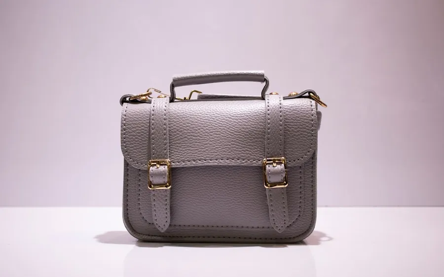 Ilustrasi mimpi tas — black leather handbag on white table