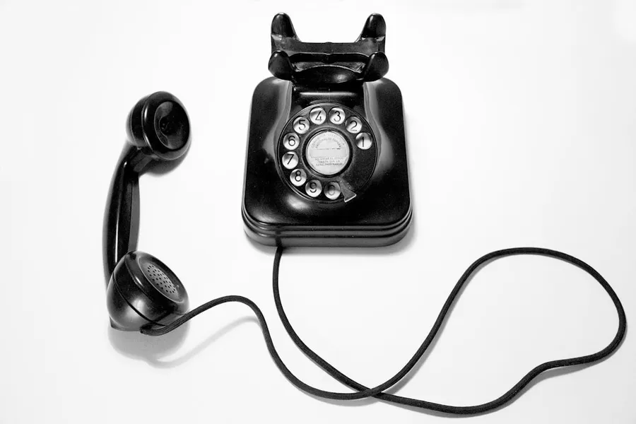 Ilustrasi mimpi telepon — black rotary dial phone on white surface