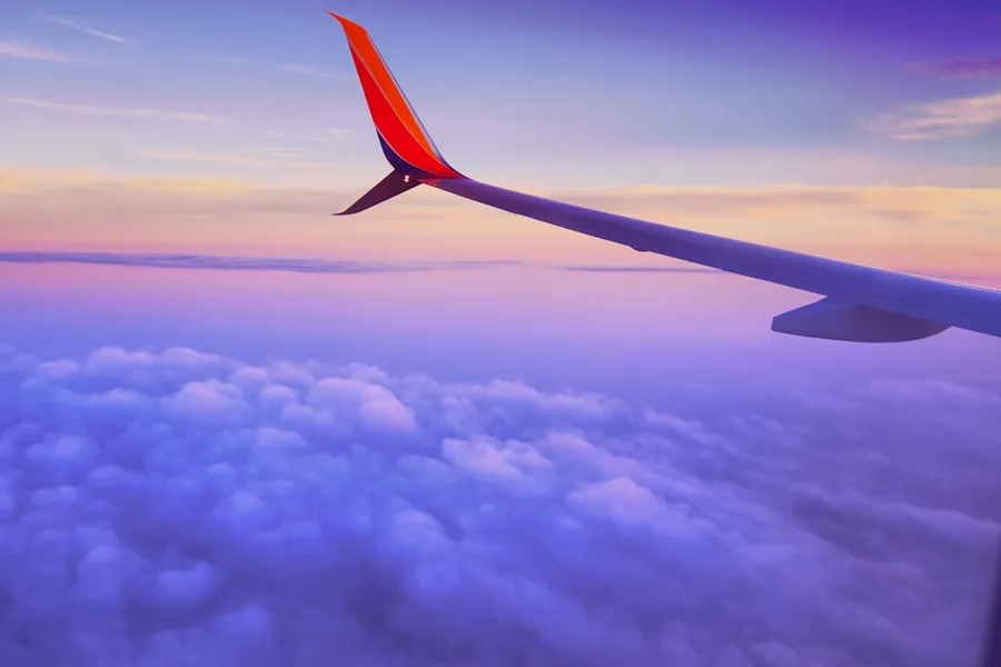 Ilustrasi mimpi terbang — person in a plane flying at high altitude taking photo of left airplane wing during daytime