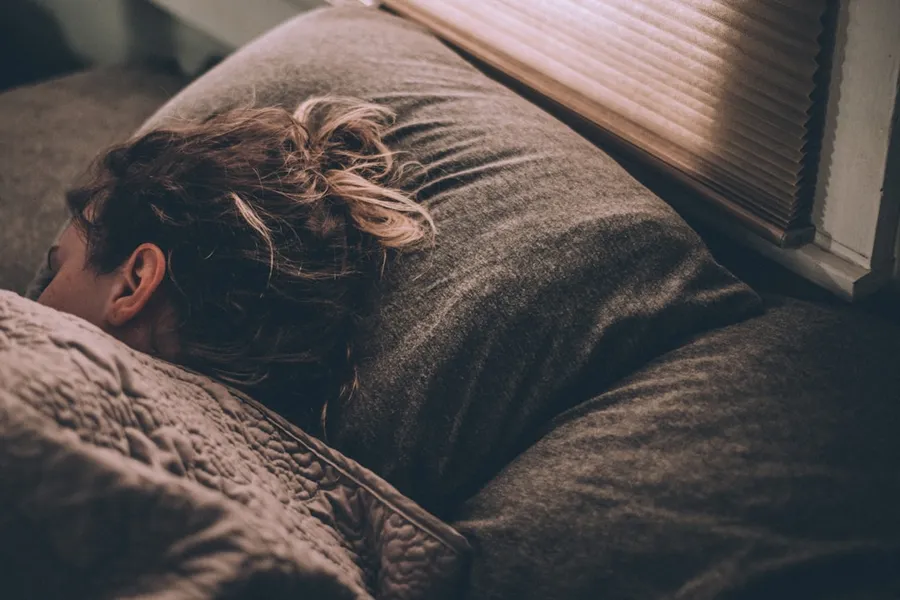 Ilustrasi mimpi tidur — woman sleeping on bed under blankets