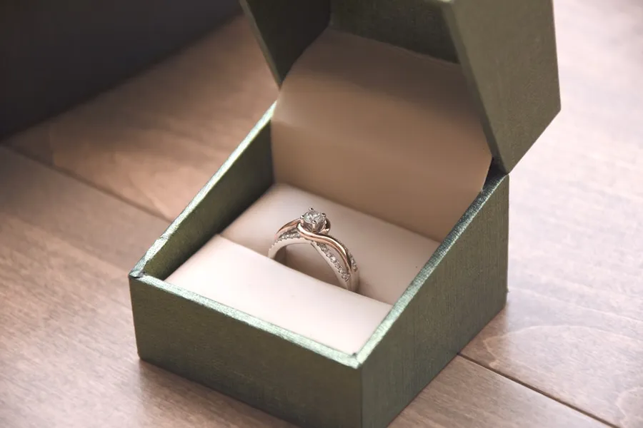 Ilustrasi mimpi tunangan — silver-colored ring with gemstone in a box